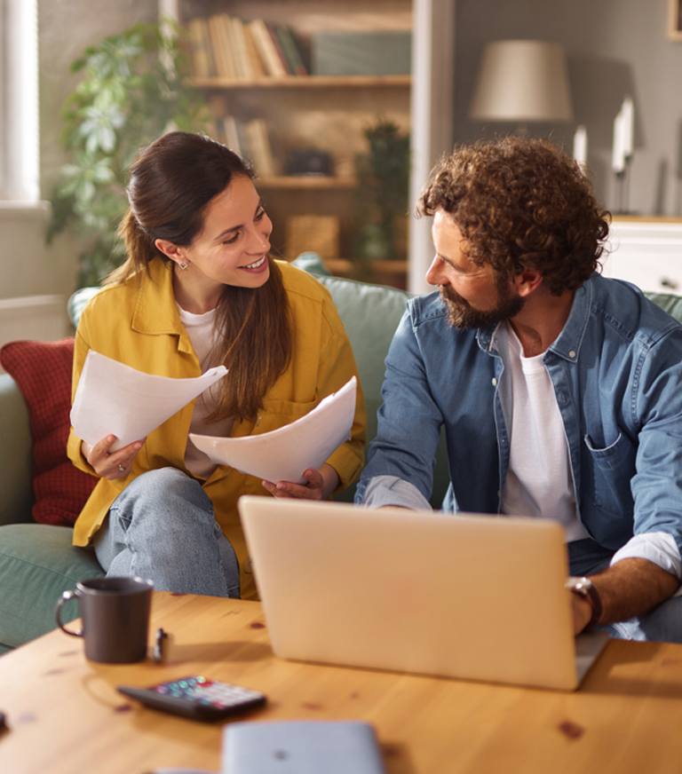 Couple reviewing documents at home with laptop