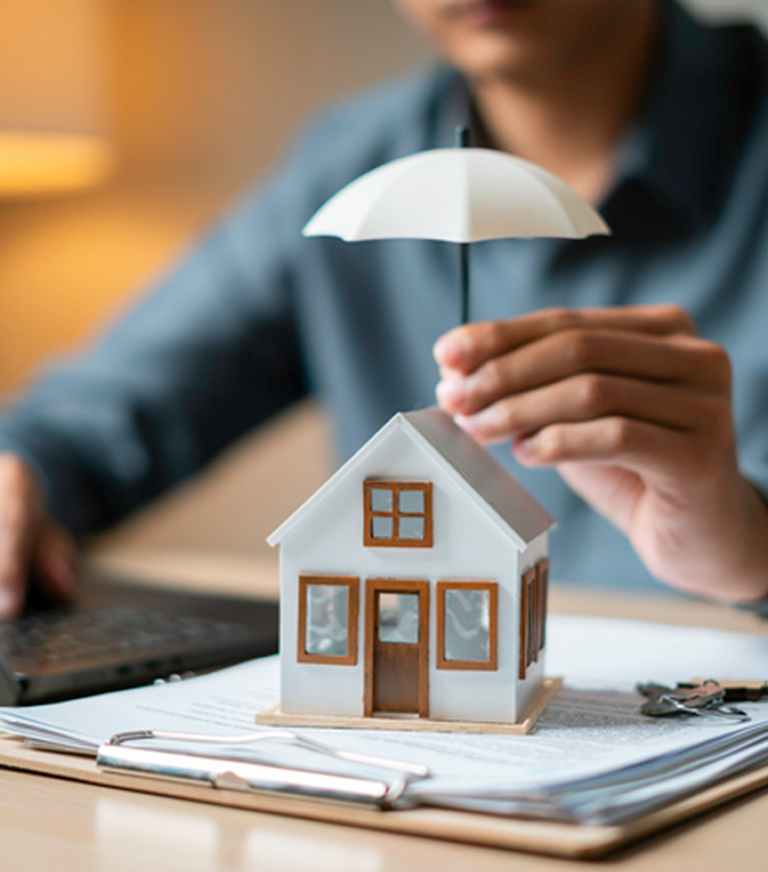 Miniature house under umbrella on desk