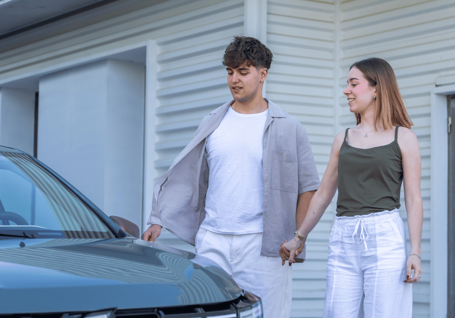Young couple holding hands by parked car