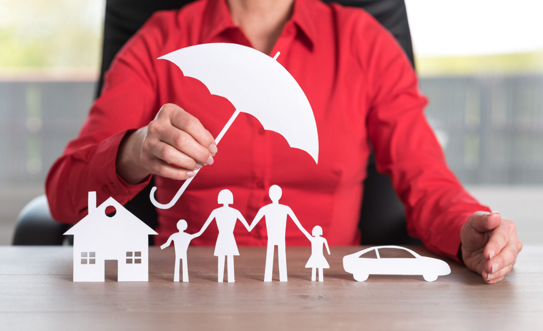 Family under umbrella with house and car