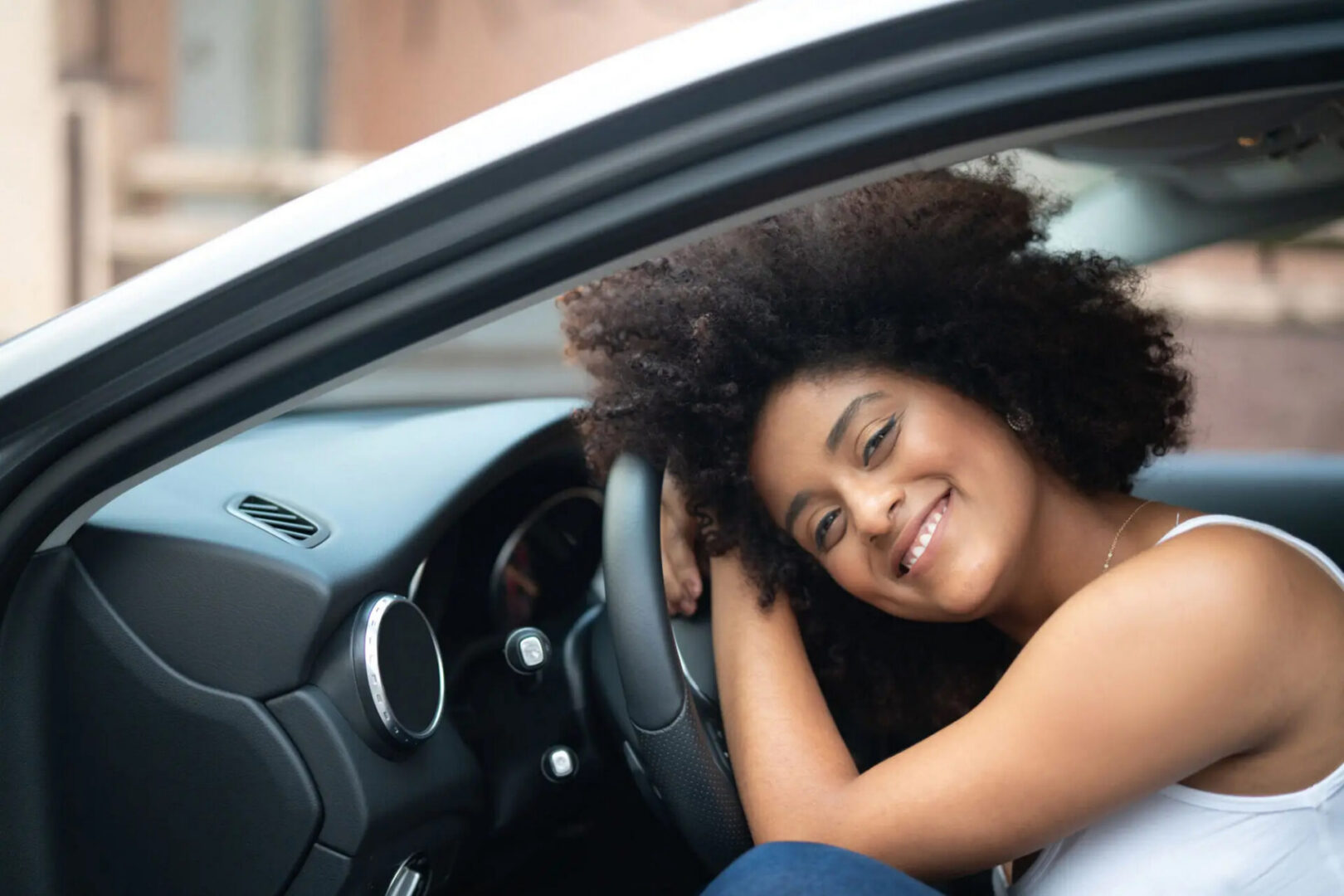 Smiling woman leaning on car steering wheel