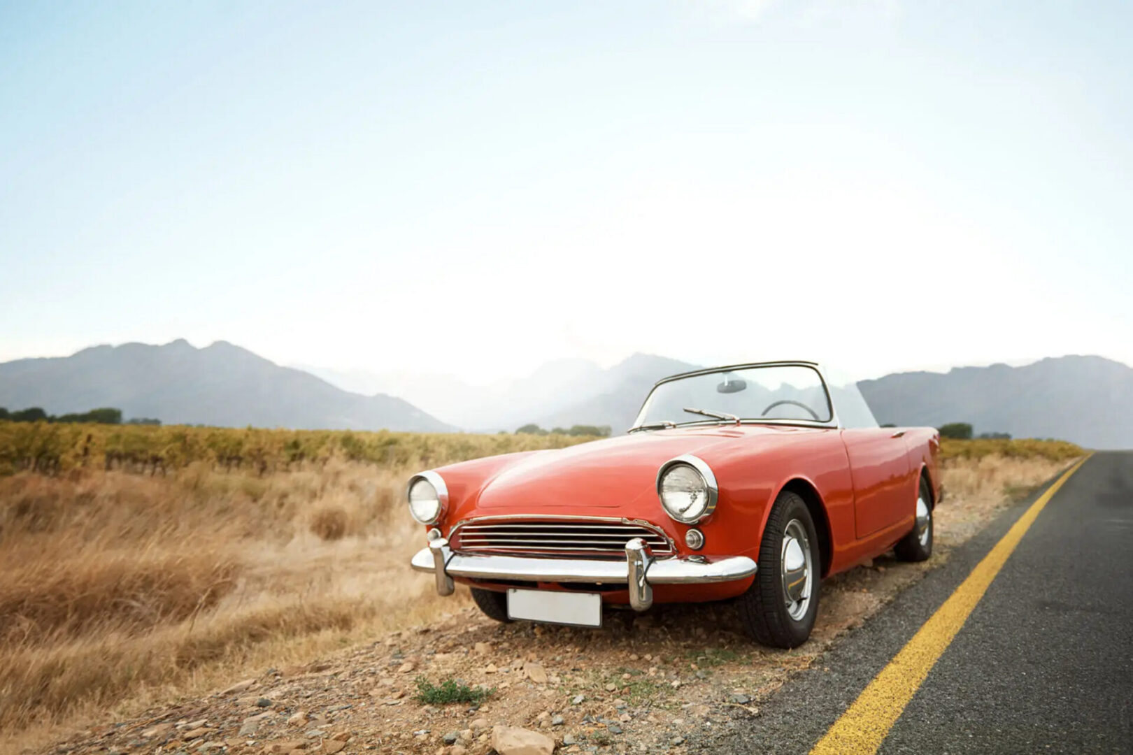 Red vintage convertible parked by roadside