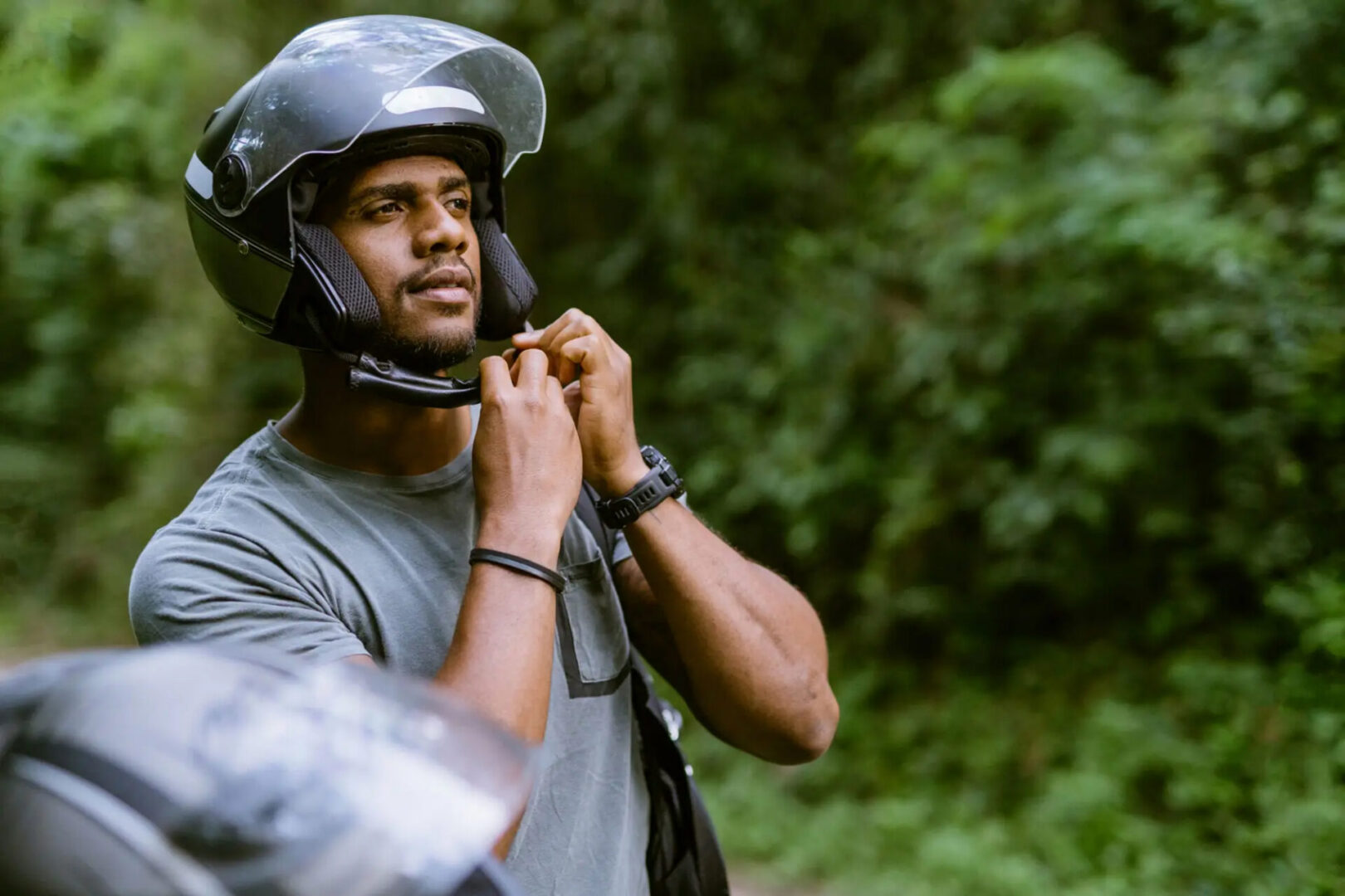 Person fastening motorcycle helmet outdoors