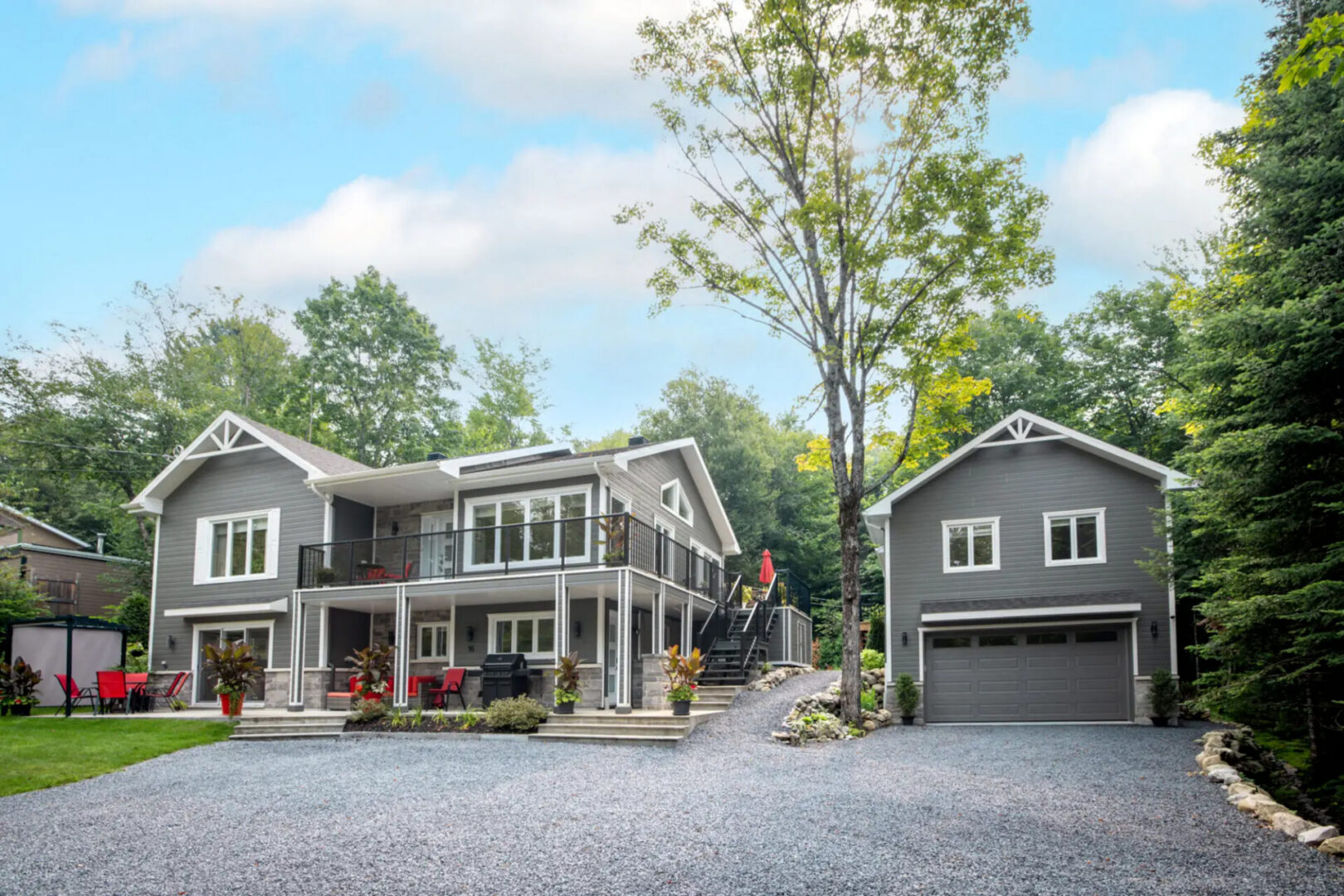 Gray two-story house with detached garage and trees