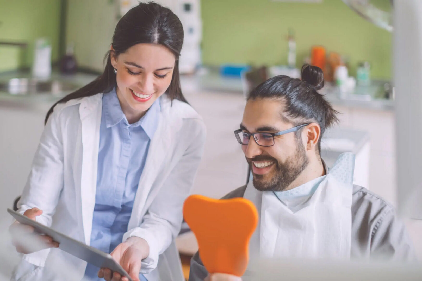 Dental professional showing tablet to smiling patient