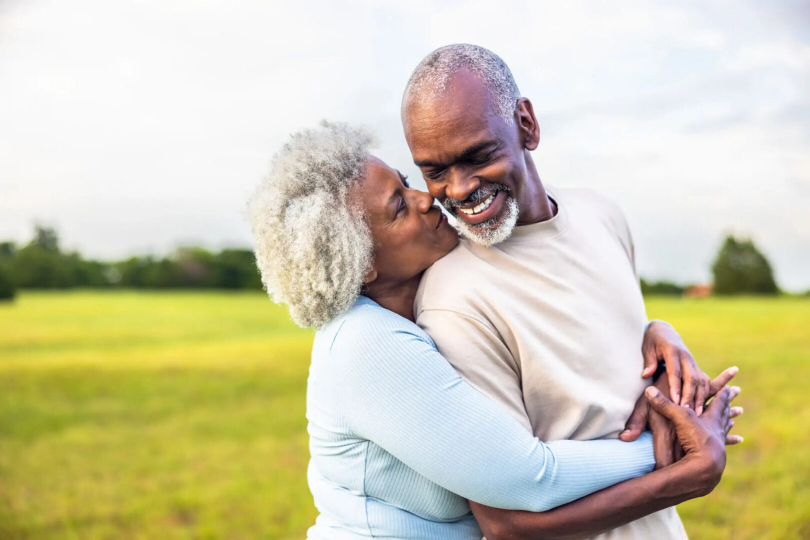 Smiling senior couple embracing in grassy field