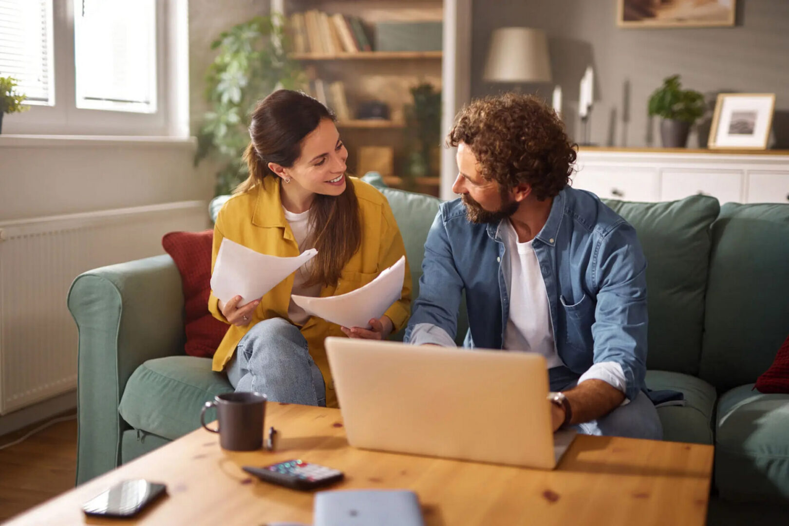 Happy couple reviewing paperwork with laptop