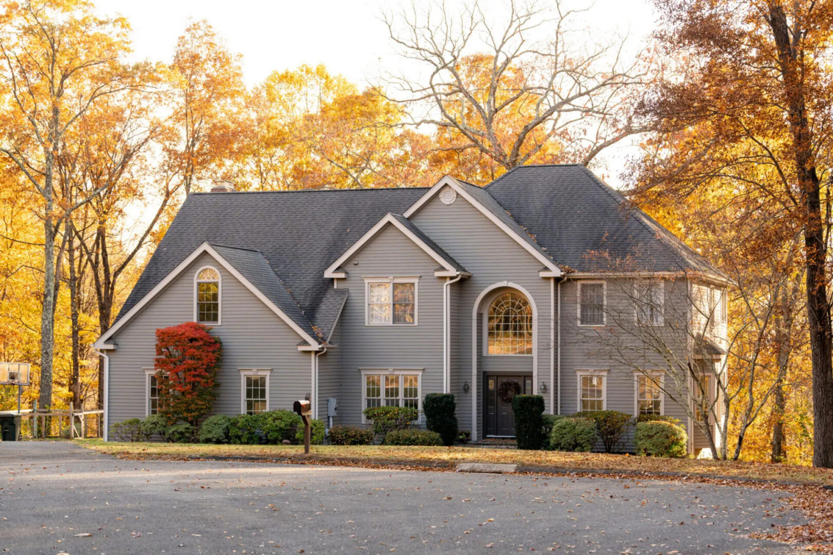 Two-story gray house amid fall foliage