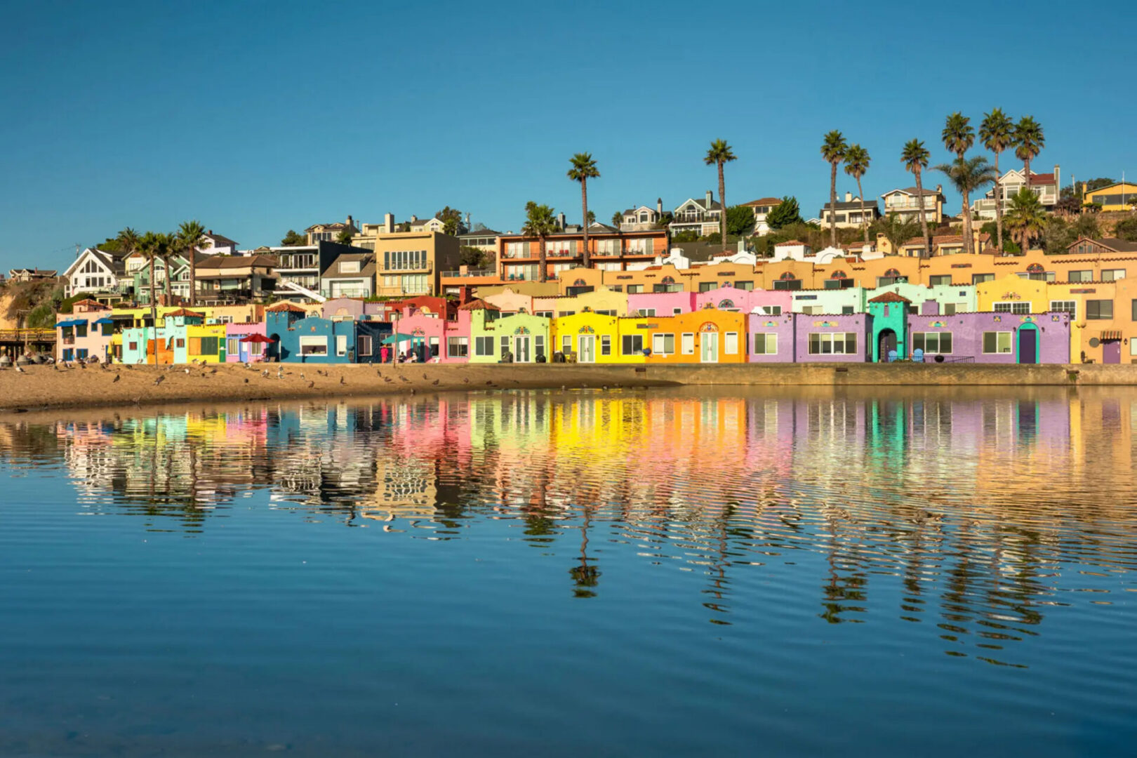 Colorful beachfront cottages reflected in calm water