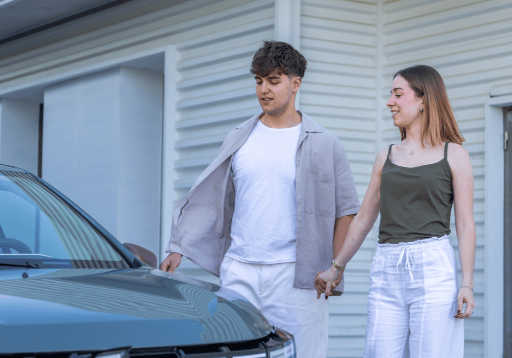 Young couple holding hands by parked car